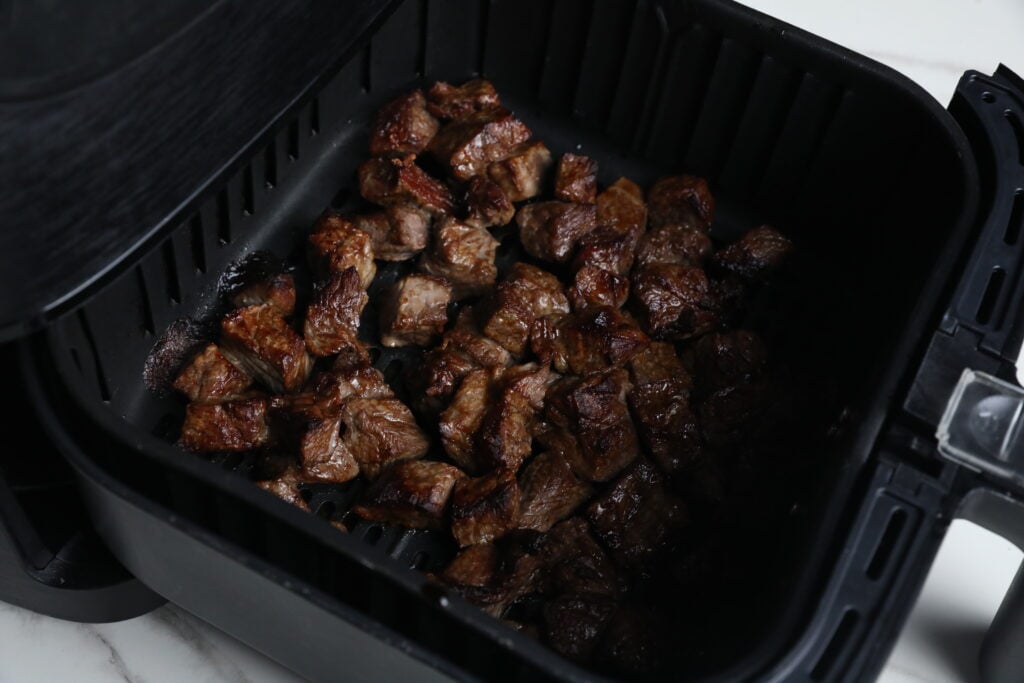 Juicy Air Fryer Steak Bites Freshly Cooked Cooked steak bites in an air fryer basket with a crispy brown exterior.