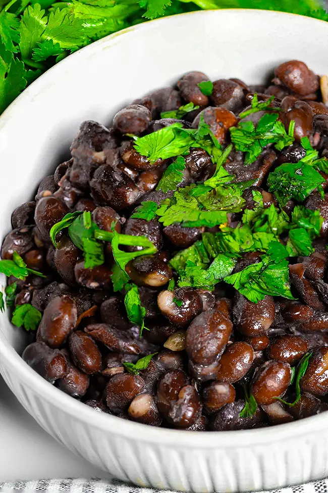 A bowl of black beans garnished with fresh cilantro.